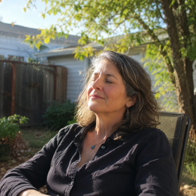 Person sitting outside with face tilted upward as if listening to birdsong — nervous system rest and safety signal response